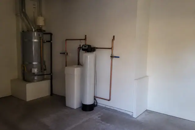 Water softener system installed with copper piping next to a water heater in a Mesa, AZ residential garage.