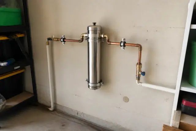 Salt-free water softener installed on a garage wall with copper pipes in Mesa, AZ.
