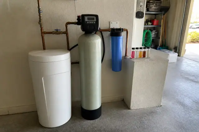 Water softener system with copper piping and a water testing kit installed in a residential garage in Mesa, AZ.