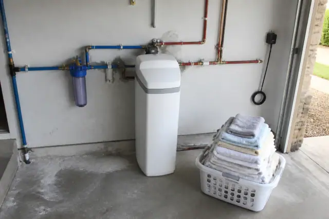 Water softener unit installed on a residential garage wall in Mesa, AZ, with neatly connected PEX piping.