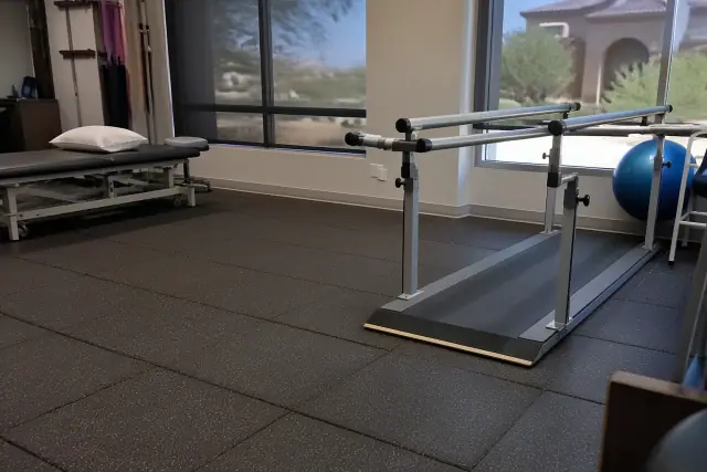 Cushioned rubber flooring installed in a physical therapy clinic in Phoenix, AZ, with parallel bars visible.