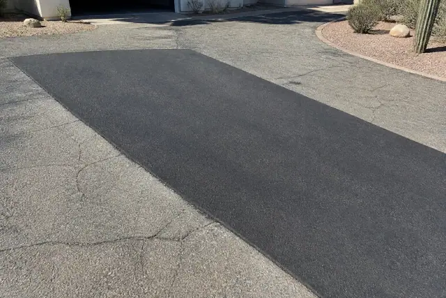 Freshly paved asphalt driveway repair showing a smooth new surface next to older pavement in Scottsdale, AZ.