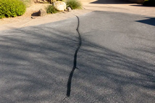 A clean asphalt crack in a residential driveway ready for repair in Scottsdale, AZ.
