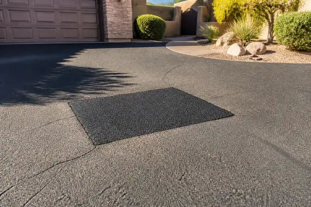 Freshly repaired asphalt patch on a residential driveway in Scottsdale, AZ.