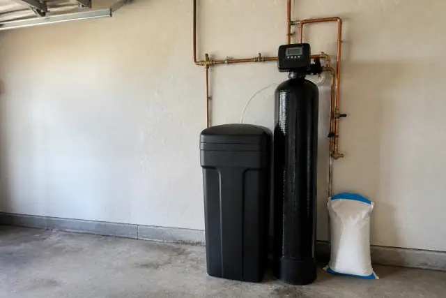 Water softener system with copper plumbing installed on a garage wall in Tempe, AZ.