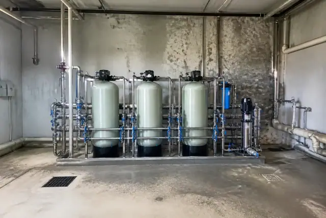 Commercial water filtration system with industrial tanks and stainless steel pipes in a mechanical room in Tempe, AZ.
