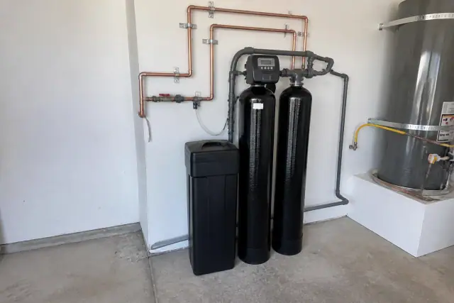 Dual-tank water softener system with copper piping installed in a residential garage in Tempe, AZ.