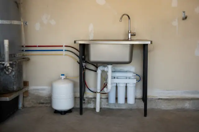 Under sink reverse osmosis water filter installation with a chrome faucet in a residential garage in Tempe, AZ.