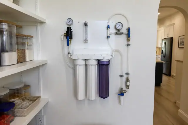 Professional water testing panel with clear tubes and gauges mounted on a pantry wall in a home in Tempe, AZ.
