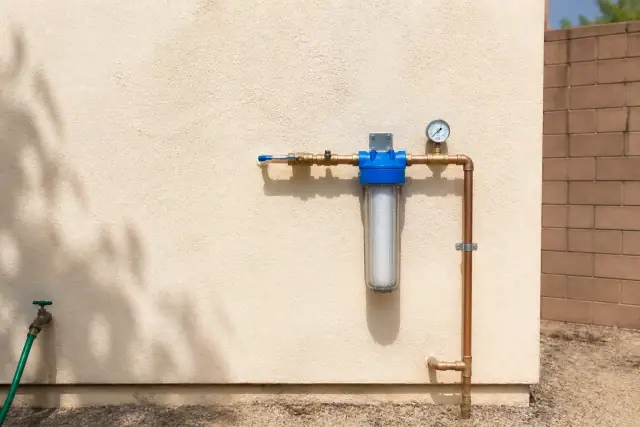 Newly installed sediment water filter with copper piping and a pressure gauge on an exterior wall in Tempe, AZ.