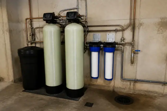 Industrial water softener system with white filter cartridges in a mechanical room in Tempe, AZ.