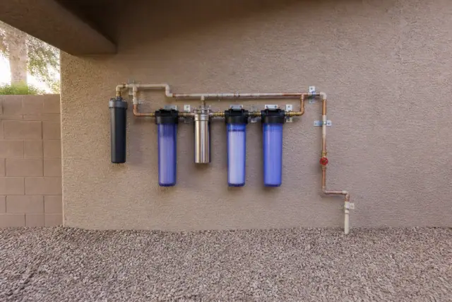 PFAS water filtration system with piping installed on an exterior wall at a home in Gilbert, AZ.