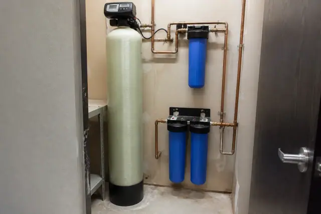 PFAS water filtration system with blue filters and copper pipes inside a utility closet in Tempe, AZ.