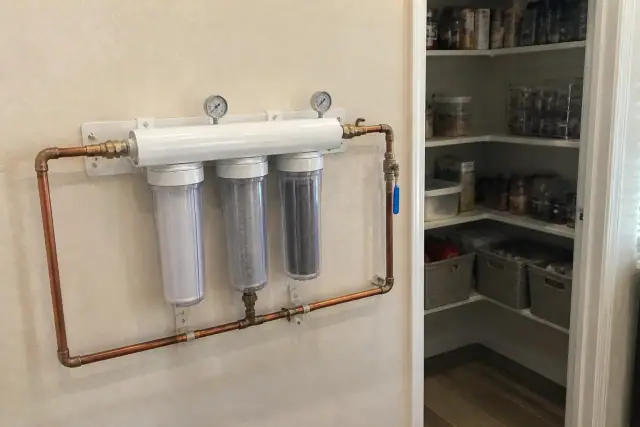 Water filtration system with copper piping and filter housings installed in a residential pantry in Tempe, AZ.