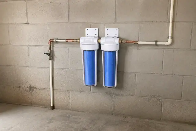 Two white sediment filter canisters mounted on a garage wall in Tempe, AZ.
