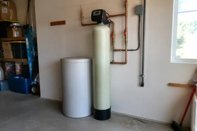 Salt-based water softener with copper plumbing installed in a residential garage in Tempe, AZ.