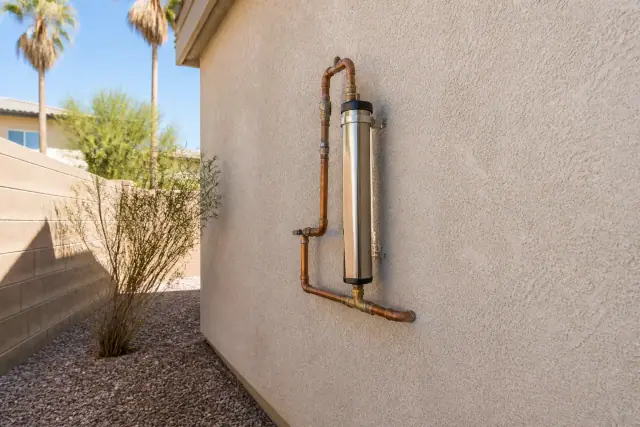 Salt-free water conditioner installed on a stucco exterior wall of a home in Tempe, AZ.