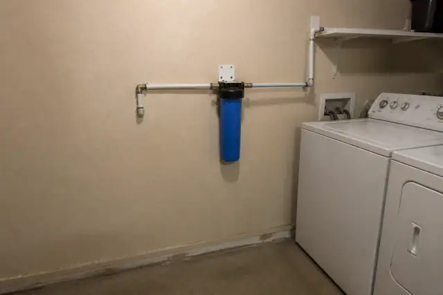 Blue sediment water filter installed with white PEX piping in a Tempe, AZ laundry room.