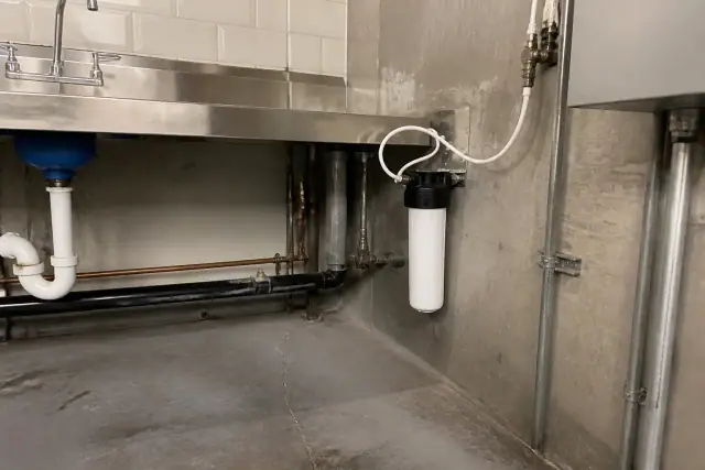 Under-sink water filtration system installed on a concrete wall in a mechanical room in Tempe, AZ.