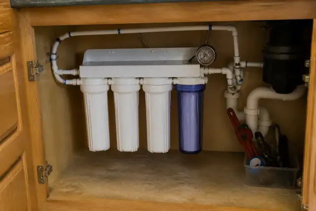 A whole-house water filtration system installed under a kitchen sink cabinet in Tempe, AZ.