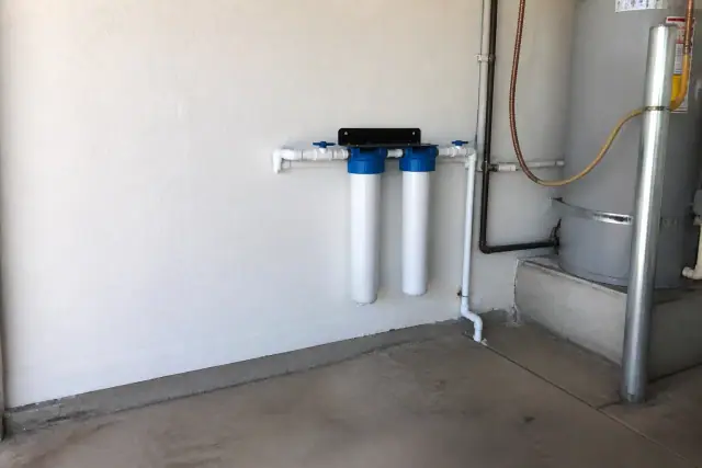 Two sediment filter housings installed on a garage wall next to a water heater in Tempe, AZ.
