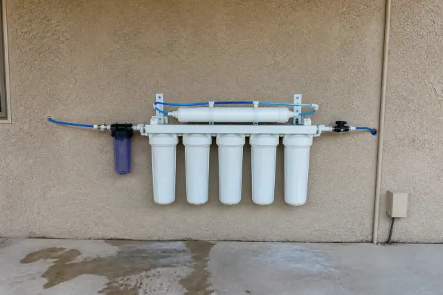 Five-stage reverse osmosis water filtration system installed on a stucco wall in Tempe, AZ.
