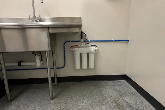 Under-sink water filtration system with PEX plumbing installed in a retail utility room in Goodyear, AZ.