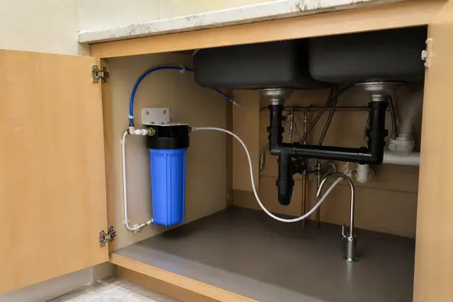 Newly installed under-sink water filtration system with clean PEX tubing in a Mesa, AZ laundry room.
