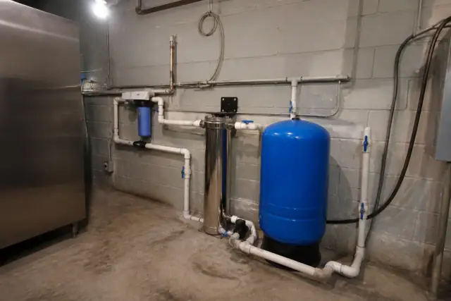 Whole-home water filtration system with blue tank and PVC piping in a Scottsdale, AZ utility room.
