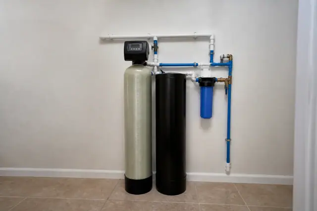 A whole-home water filtration system with two tanks and blue piping installed against a pantry wall in Chandler, AZ.