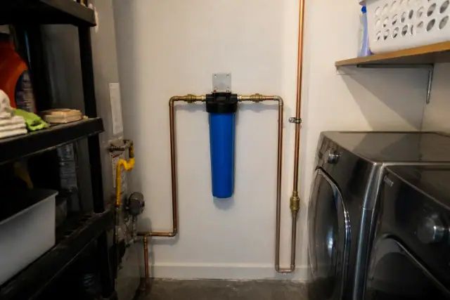New blue whole house water filter installed with copper piping in a Tempe, AZ laundry room.